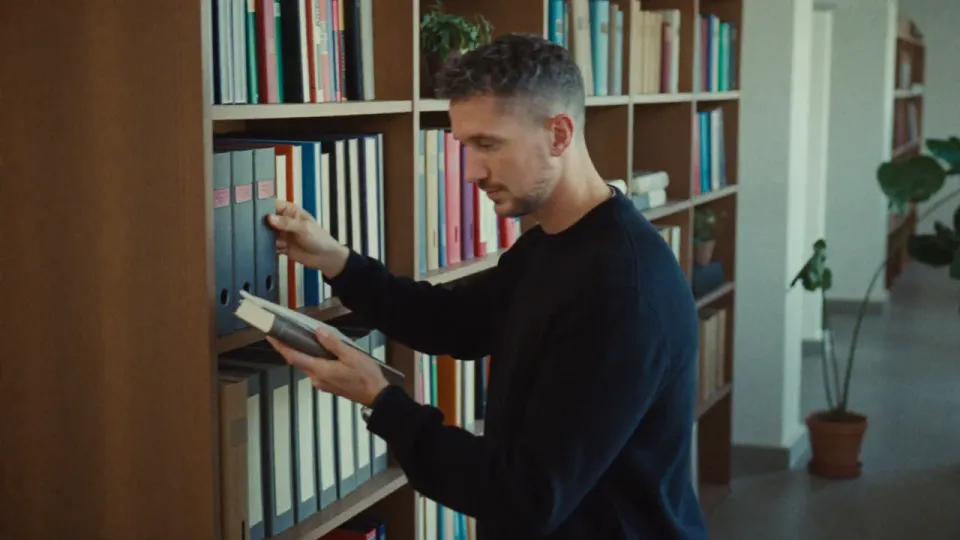 Willem Nales zoekt een naslagwerk uit een boekenkast
